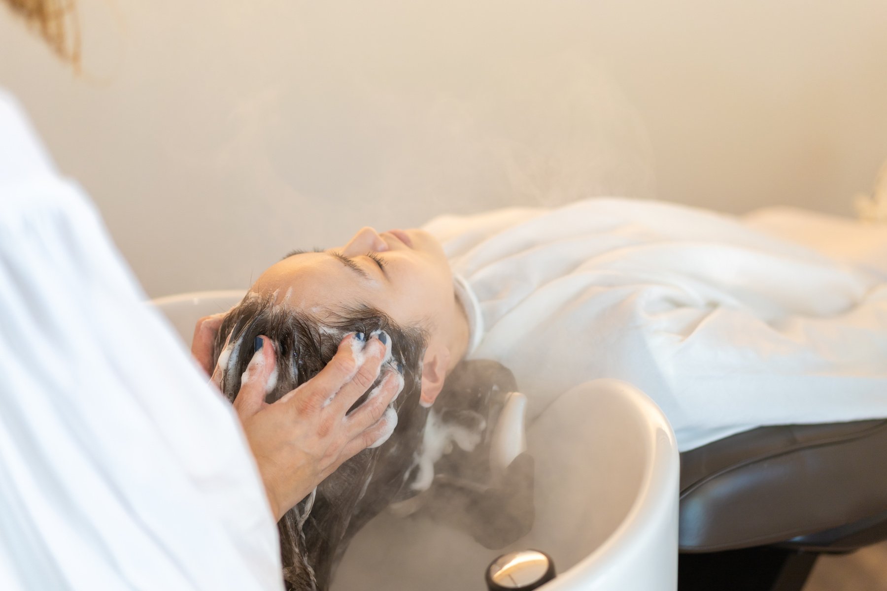 Hairdresser shampooing hair at shampoo table